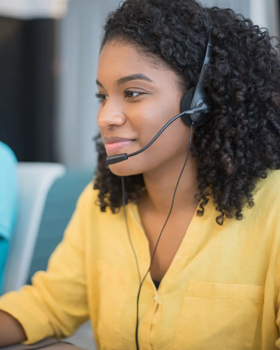 Outsourced call center agent wearing a headset handling a customer support call at her workstation